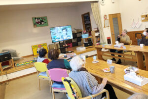 介護施設の共用スペースで入居者がテレビを見ている風景